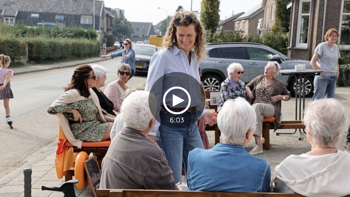 Buren zitten op de rollende banken in de straat en praten met elkaar, met een afspeelknop van de video